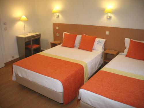 a hotel room with two beds with orange and white at Estrela dos Anjos Guesthouse in Lisbon