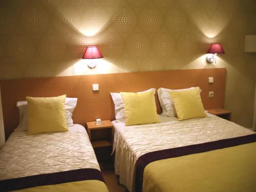 a hotel room with two beds and two lamps at Estrela dos Anjos Guesthouse in Lisbon