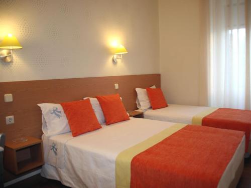 um quarto de hotel com duas camas com almofadas laranja e amarela em Estrela dos Anjos em Lisboa