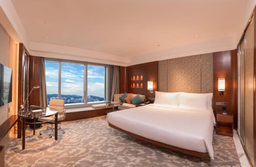 a bedroom with a large white bed and a desk at Crowne Plaza Macau, an IHG Hotel in Macau