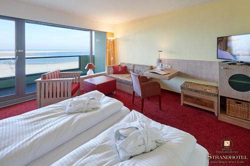 a hotel room with two beds and a television at Strandhotel VierJahresZeiten in Borkum
