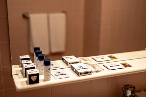 a bathroom counter with hygiene products and a mirror at Hotel Diana in Valdobbiadene