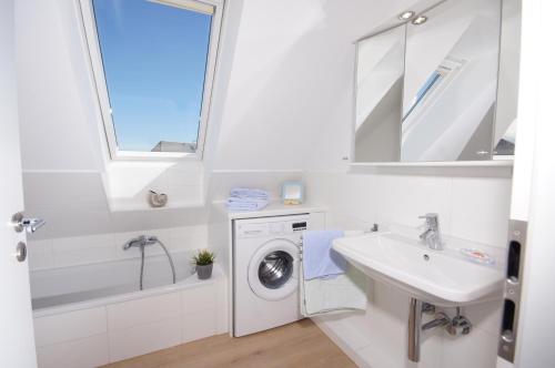uma casa de banho branca com uma máquina de lavar roupa e um lavatório em Ferienhaus II Wiesenblick em Grömitz