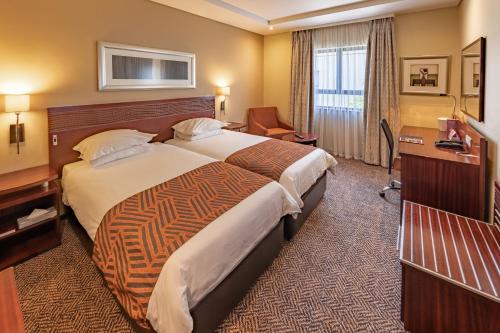 a hotel room with a large bed and a desk at City Lodge Hotel at OR Tambo International Airport in Kempton Park