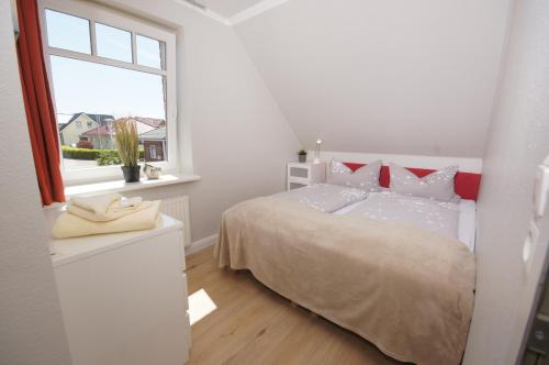 a white bedroom with a bed and a window at Ferienwohnung Krähenberg in Grömitz