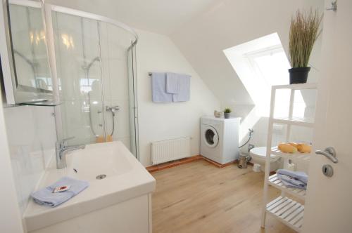 uma casa de banho branca com um chuveiro e um lavatório. em Ferienwohnung Krähenberg em Grömitz