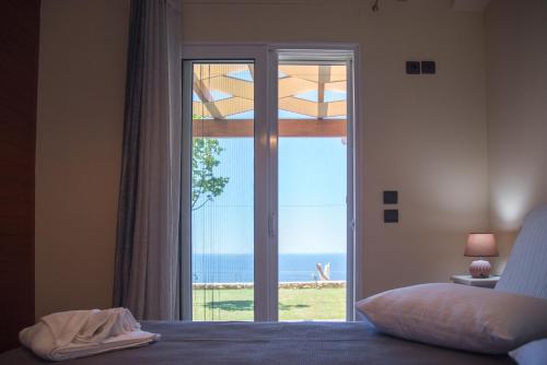 - une chambre avec une grande porte en verre offrant une vue sur l'océan dans l'établissement Blue Horizon Villas with Private Pool & Sea View, à Plateies