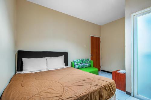 a bedroom with a bed and a green chair at Griya Stadion in Semarang