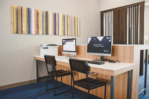 an office with a desk with a computer and two chairs at Holiday Inn Express & Suites Omaha Downtown Old Market by IHG in Omaha