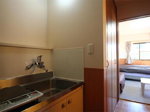 una pequeña cocina con fregadero y un dormitorio en Karuizawamura Hotel en Karuizawa
