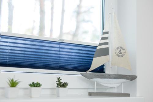 a bathroom with a sailboat on a sink in a window at APARTAMENT 9B BLUE MARINE Poddąbie Basen Odkryty Brodziki Plac Zabaw in Poddąbie