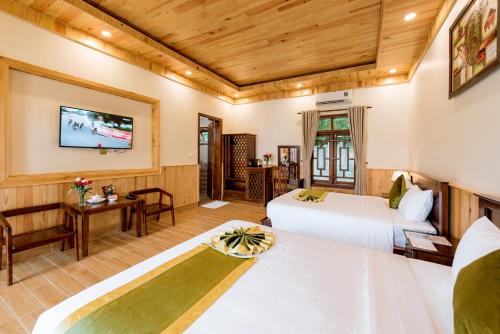 a hotel room with two beds and a tv at Bungalow Sáng Tươi Mountains in Phu Quoc