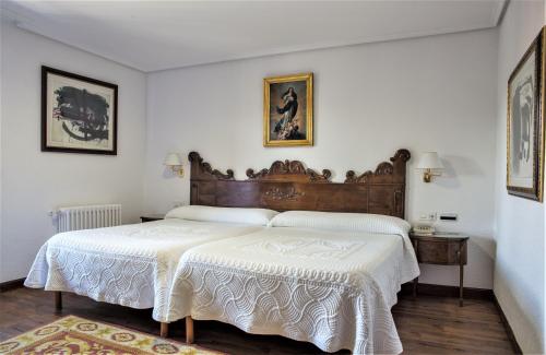 sypialnia z dużym łóżkiem z drewnianym zagłówkiem w obiekcie Hotel Museo Los Infantes w mieście Santillana del Mar