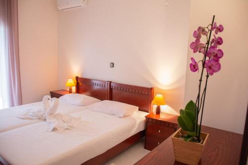 a bedroom with a bed and a vase with purple flowers at Mokos Rooms in Perdika