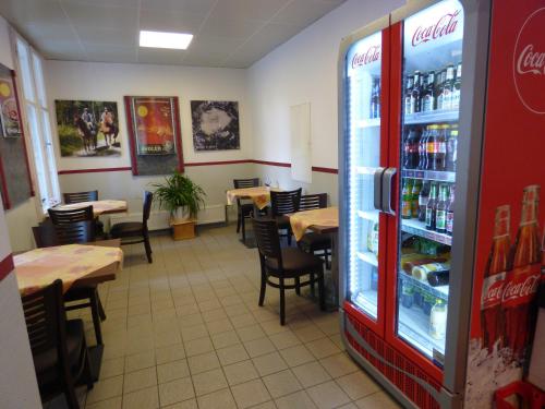 a restaurant with tables and a cocacola refrigerator at Gasthof & Fleischerei Endler in Rheinsberg