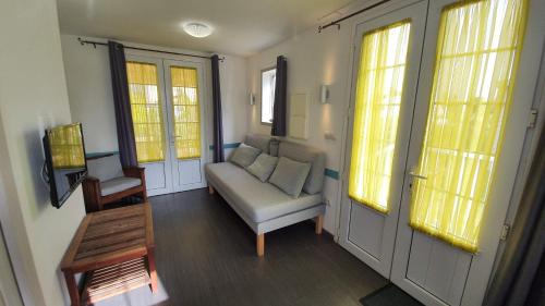 ein Wohnzimmer mit einem Sofa und 2 Fenstern in der Unterkunft Villa de charme - la plaine des cafres in La Plaine des Cafres