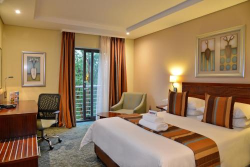 a hotel room with two beds and a desk at City Lodge Hotel Fourways in Johannesburg