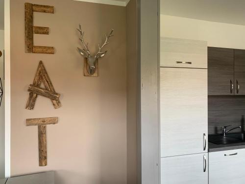 a kitchen with white cabinets and a cross and a deer head on the wall at Harzstübl25 in Sankt Andreasberg