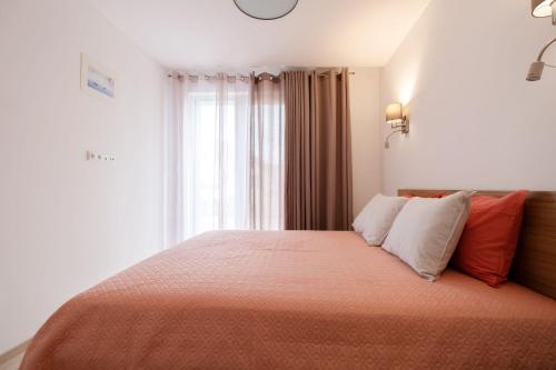 - une chambre avec un lit doté de draps orange et une fenêtre dans l'établissement Riverside Ronze Apartment, à Palanga