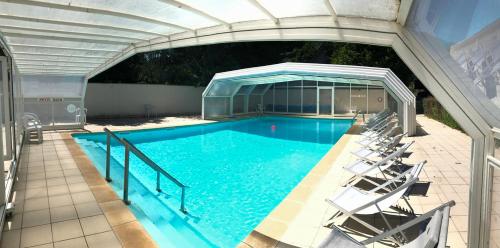 a large swimming pool with chairs in a building at Auberge de la Vallée d'Ossau in Izest