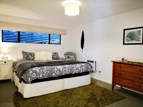 a bedroom with a bed and a dresser and a window at Park to Mountains Apartment in Arrowtown