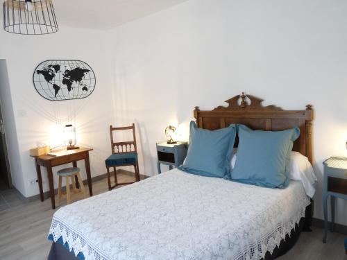 1 dormitorio con 1 cama con almohadas azules en La Bouillarde, en Suze