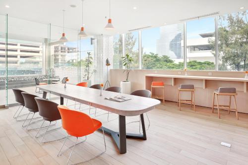 a dining room with a table and chairs and windows at HARRIS Hotel & Conventions Bundaran Satelit Surabaya in Surabaya