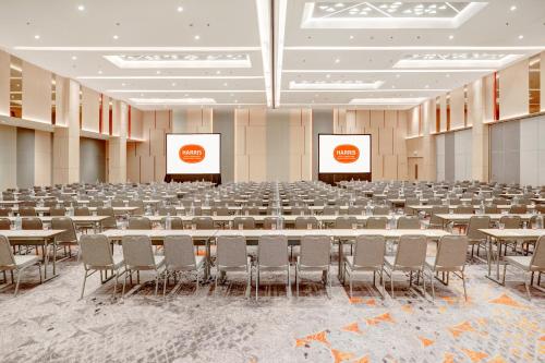 a large room with tables and chairs and two screens at HARRIS Hotel & Conventions Bundaran Satelit Surabaya in Surabaya