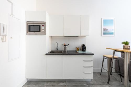 une cuisine blanche avec un évier et un micro-ondes dans l'établissement 1 CASSINI - Magnifique 2 pièces place Garibaldi - Balcon, à Nice