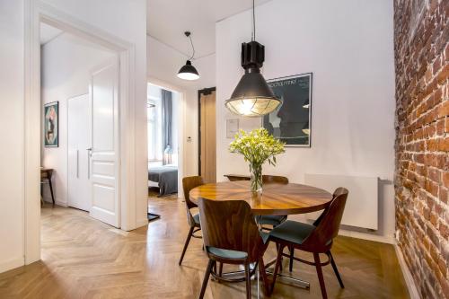 a dining room with a table and chairs and a brick wall at Relaks Apartamenty in Kraków
