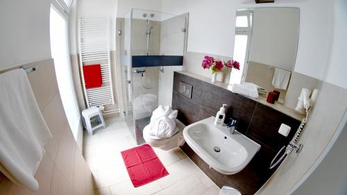 a white bathroom with a sink and a shower at Aura Hotel in Timmendorfer Strand