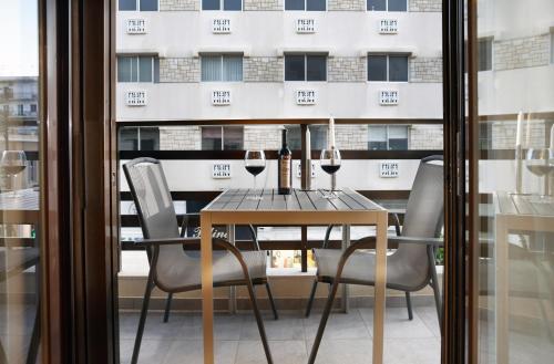 a table with wine glasses and chairs in front of a building at Armi Luxury Apartment in the Heart of the City in Chania Town
