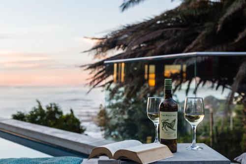 a bottle of wine and two glasses on a table with a book at Living Hotel Lion's Eye in Cape Town