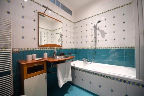 y baño con azulejos azules y blancos, bañera y lavamanos. en Suite art Pigneto, en Roma