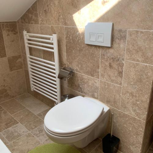 a bathroom with a white toilet in a room at Dachgeschoss Ferienwohnung mit Charme - Top floor apartment with charme in Fischbachau
