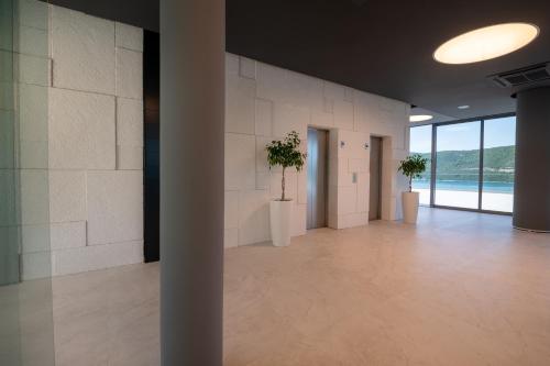 a large room with white walls and two potted plants at Hotel VAPORE in Neum