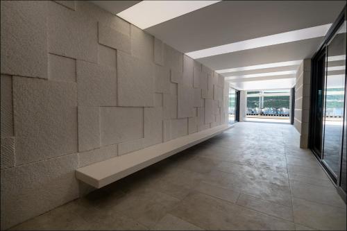 a hallway with a stone wall with a bench at Hotel VAPORE in Neum