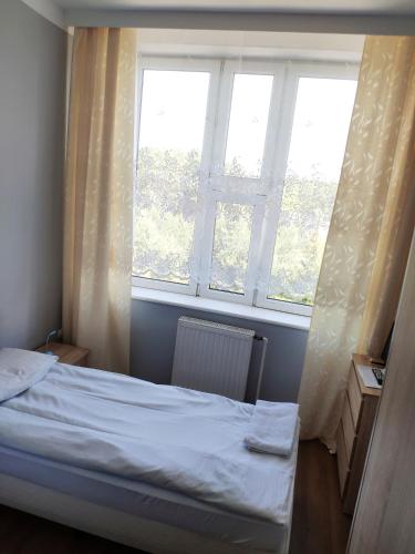 a small bedroom with a bed and two windows at Hotel Akor in Bydgoszcz