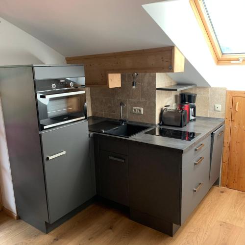 a kitchen with a stainless steel refrigerator and a sink at Dachgeschoss Ferienwohnung mit Charme - Top floor apartment with charme in Fischbachau