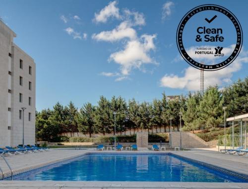 a sign that reads clean and safe next to a swimming pool at VIP Executive Santa Iria Hotel in Santa Iria da Azóia