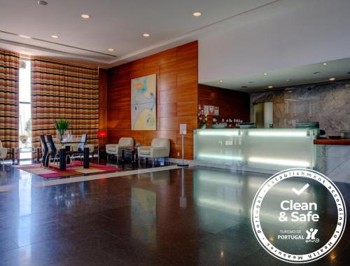 a lobby with a table and chairs in a building at VIP Executive Santa Iria Hotel in Santa Iria da Azóia