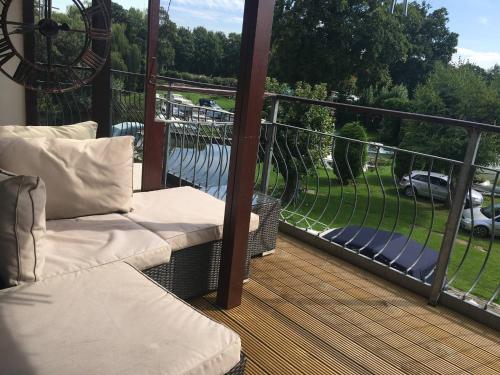 a balcony with a couch and a view of the water at Waterfront House In The Heart Of St Neots in Saint Neots