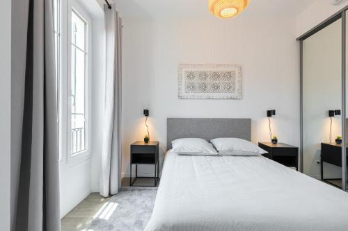 une chambre blanche avec un grand lit et deux fenêtres dans l'établissement 3 FODERE - Magnifique 2 pièces - Quartier du Port - Dernier étage, à Nice