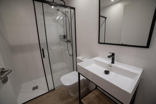 La salle de bains blanche est pourvue d'un lavabo et d'une douche. dans l'établissement Loft en Zarautz con Parking Hator 2, à Zarautz