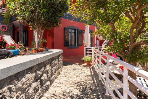 a red house with trees and a white fence at Casa das Camélias in Arco da Calheta