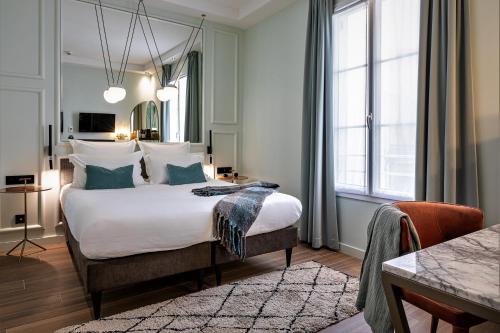 um quarto com uma cama grande com lençóis brancos e almofadas azuis em Hôtel Veryste & Spa Paris em Paris