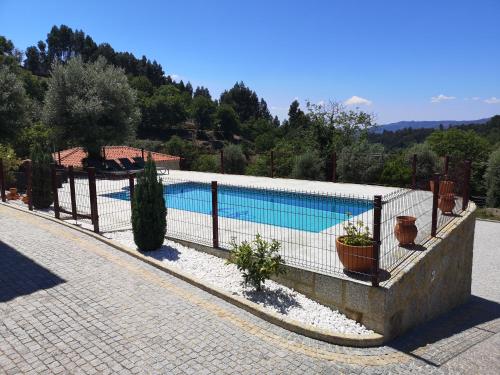 a swimming pool with a fence next to a house at Casa Zé Manel - Turismo Rural in Paranhos