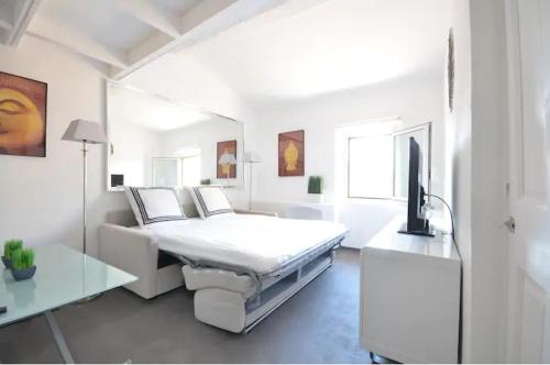 a white bedroom with a bed and a tv at Studio centre ville Saint Tropez avec parking in Saint-Tropez