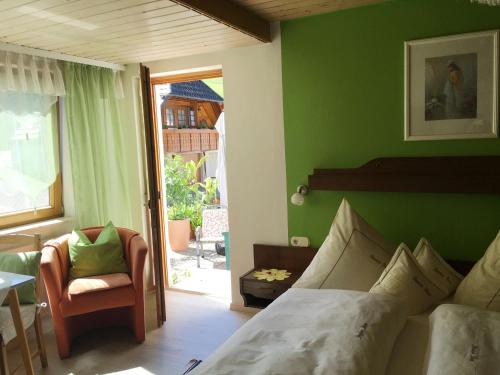 ein Schlafzimmer mit einem Bett, einem Stuhl und einem Fenster in der Unterkunft Pension Haus Rose in Oberharmersbach