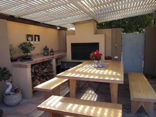 a patio with a table and benches and a television at La Roche Guest House in Cape Town